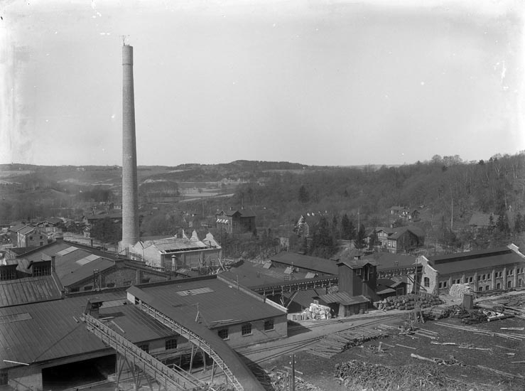 Enligt fotografens noteringar: "Extriör af Munkedals fabrik. Obs arbetare öfverst på skorsten omkring 1913."