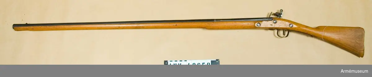 Grupp E XIV.
Afrikanskt gevär med flintlås. Loppets relativa längd är 72,4 kal. Rörkor och laddstock saknas. Låset signerat "BARKER".