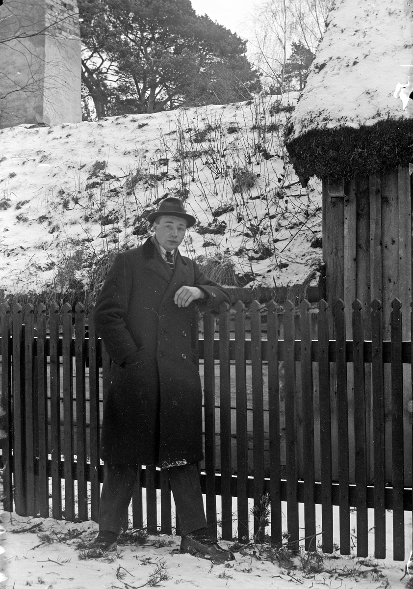 Gustav Andersson står lutad mot staketet vid Ryggåsstugan i Jönköpings Stadspark. Den kommer från Sjöaryds by, Markaryds socken, Sunnerbo härad.