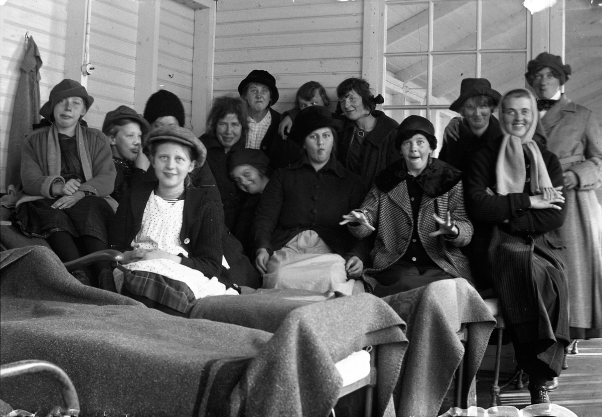 Fjorton kvinnor står vid eller sitter på en rad sängar, på träverandan vid Lungkliniken i Eksjö.