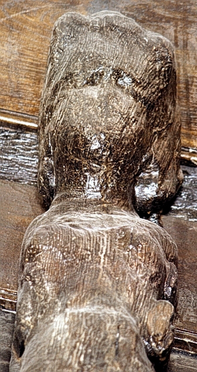 Nereid med tjockt, lockigt hår. Bar överkropp. Armarna är ersatta av bladornament. Nedre delen av kvinnofiguren består av en fiskstjärt slingrar sig kring stjärten till en fisk eller delfin, vars huvud är synligt vid skulpturens fotända.

Bakstycket är kraftigt och snidat i ett med skulpturen. Baksidan är försedd med hak eller urtag. Skulpturens profil är svagt S-formad.
Skulpturen är mycket kraftigt sliten och stora delar av ansiktet och bålen är utplånade.

Text in English: Nereid with thick curly hair with the arms replaced by leafy ornamentation. The lower part of her body consists of a fish tail that is entwined with the tail of a fish or dolphin whose head can be seen at the foot of the sculpture.

The backboard is robust and carved in one piece with the figure. The back side of the backboard was carved with hollowed out grooves. The profile is slightly S-shaped.
The sculpture is in a very bad condition, with a large section of the face and trunk worn away.