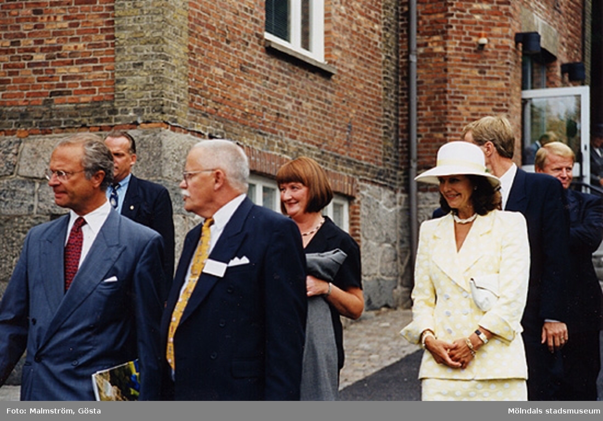 Från vänster är Kung Carl XVI Gustaf, en säkerhetsman, kommunalrådet Bengt Odlöw, Mari-Louise Olsson, Drottning Silvia, Karl-Gunnar Nordanstad samt landshövding Göran Bengtsson. De går utanför Mölndals Museum 1997.