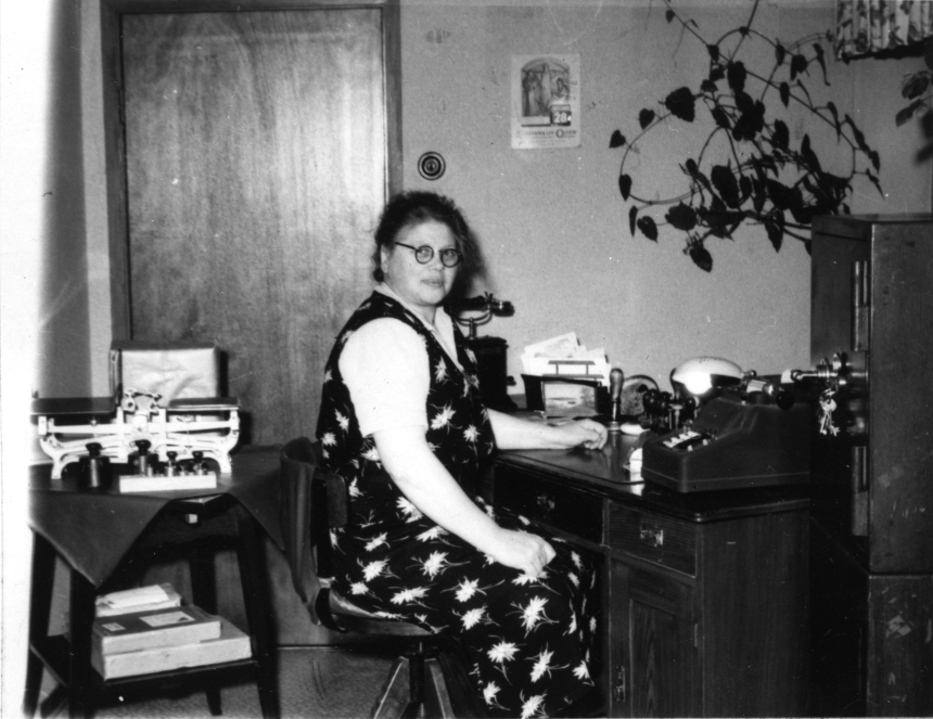 Vid skrivbordet poststationsföreståndarinnan Eva Hanner.
Poststationen i Bollerup inrättades 1874 och drogs in 1979.