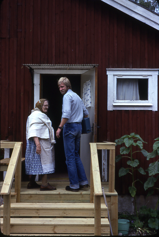 Lantbrevbärare Mikael Mattsson har kommit till Rockstaberg. Han står med Ester Gustavsson på trappan till hennes hus. De är på väg in genom dörren. Kassaskrinet har han under armen.