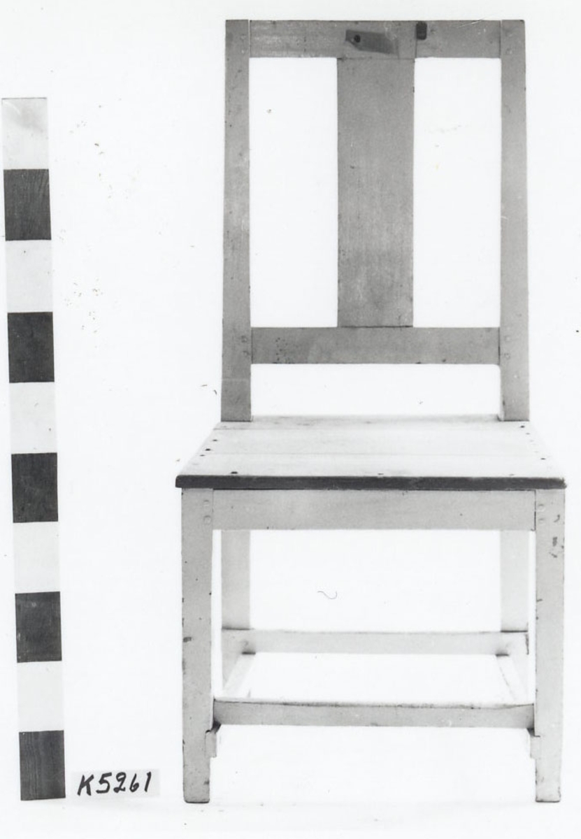 Stol av furu, vit- och gråmålad. Större. Rak modell med raka fyrsidiga ben samt rektangulär ryggbricka. Märkning: 1826.