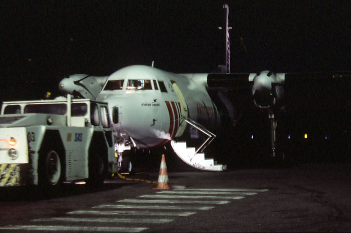 Lufthavn, 1 fly fra SAS med landgangen nede.  1 taxekjøretøy foran flyet.  Tatt i mørket.