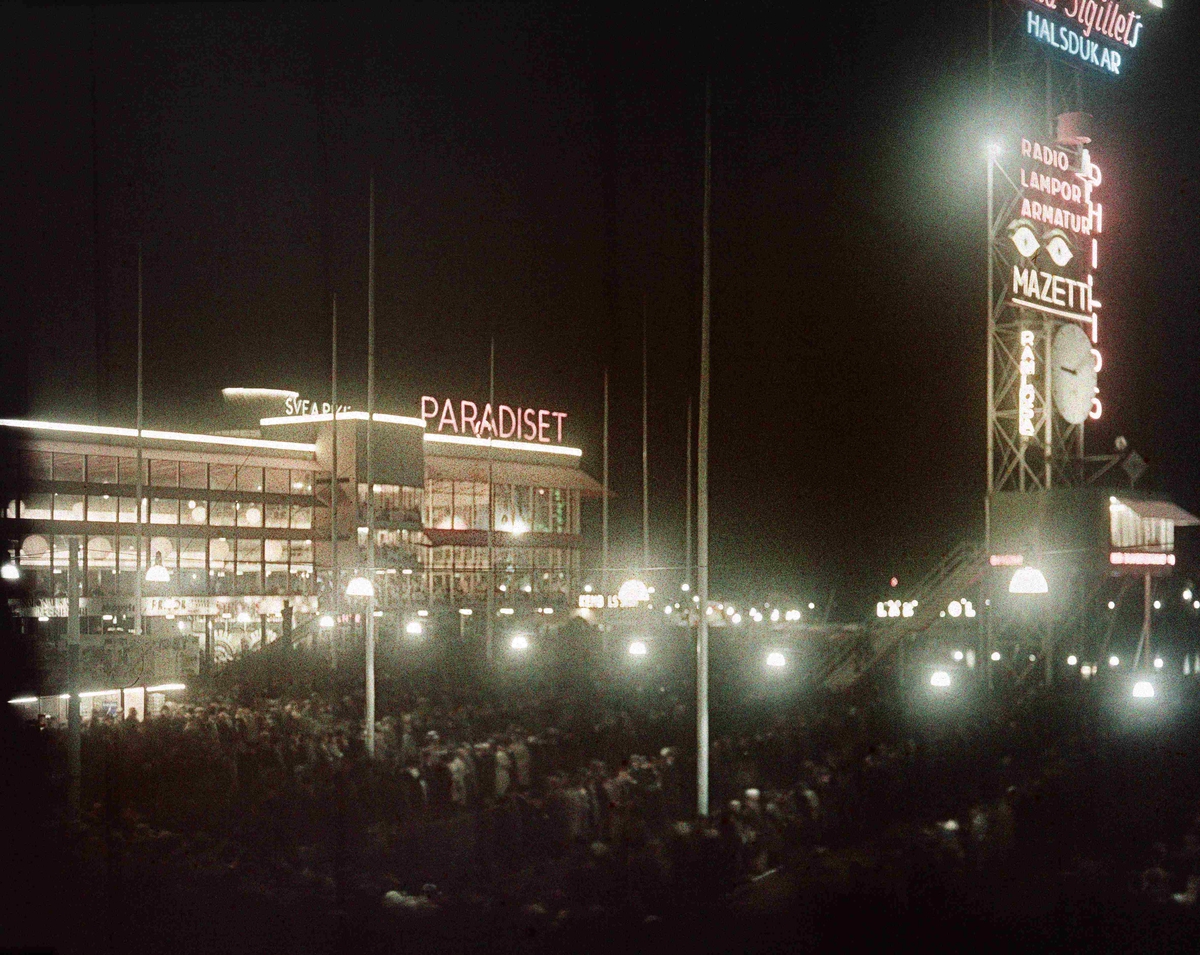 Restaurang Paradiset och masten med pressläktaren i neonbelysning. Nattbild. Arkitekt till Paradiset: Gunnar Asplund, arkitekt till masten: Sigurd Lewerentz.
Stockholmsutställningen 1930
