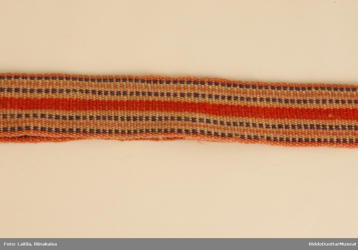 Porsanger skallebånd. Dette mønsteret er omtrent det samme som i Karasjok, Tana, Masi og Kautokeino. Fargene er veldig falmet. Mønstertråder i blått og rødt. Mønsteret er enkelt, langsgående og vekselsvis mellom blått og rødt fra ende til annen. Langs hele midtdelen av båndet er det en 7 mm bred rød del. 
I den ene enden er det sydd fast bárggeš med ulltråd, i den andre er det sydd fast en lang bit av sisti som skal festes til skotøyet. På det andre båndet er det ikke sisti, men en lang tøybit. Bárggeš er i samme farger som båndet.