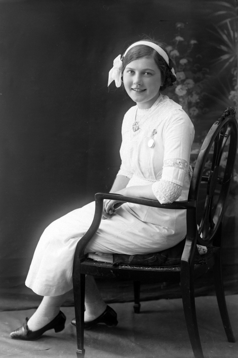 Studioportrett av ung kvinne i stol.