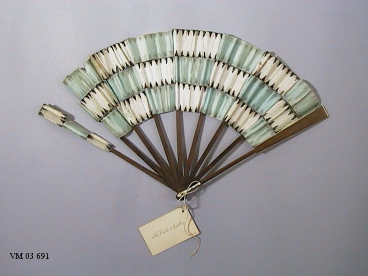 Solfjäder från Kina, år 1780.

2 = Sidenremsor med tryckt motiv fastlimmade på en brun trästomme, vit-blå.