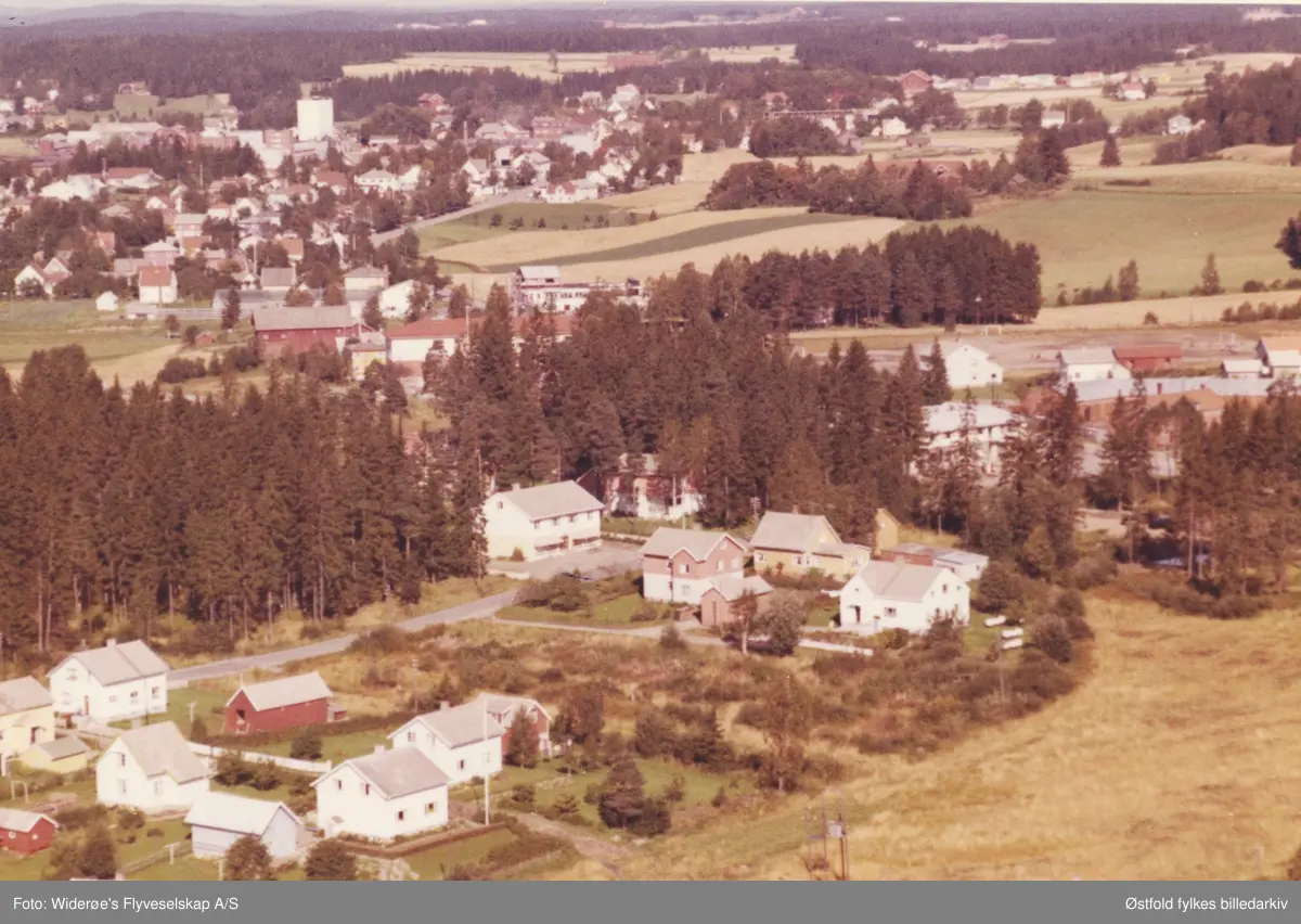 Skråfoto av boligfeltet Bergenhus, 11. sept. 1963. 
Butikken Bergenhus Handel ligger midt i motivet.

Rakkestadbyen sees i bakgrunnen.