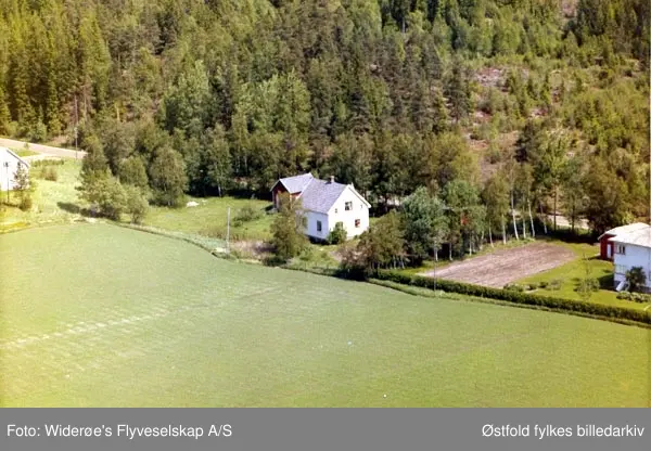 Skråfoto av villa på Kjempeåsen i Rakkestad, 13. juni 1964.
Skammelsrud kolonialforretning lå noen hus bortenfor til høyre.
