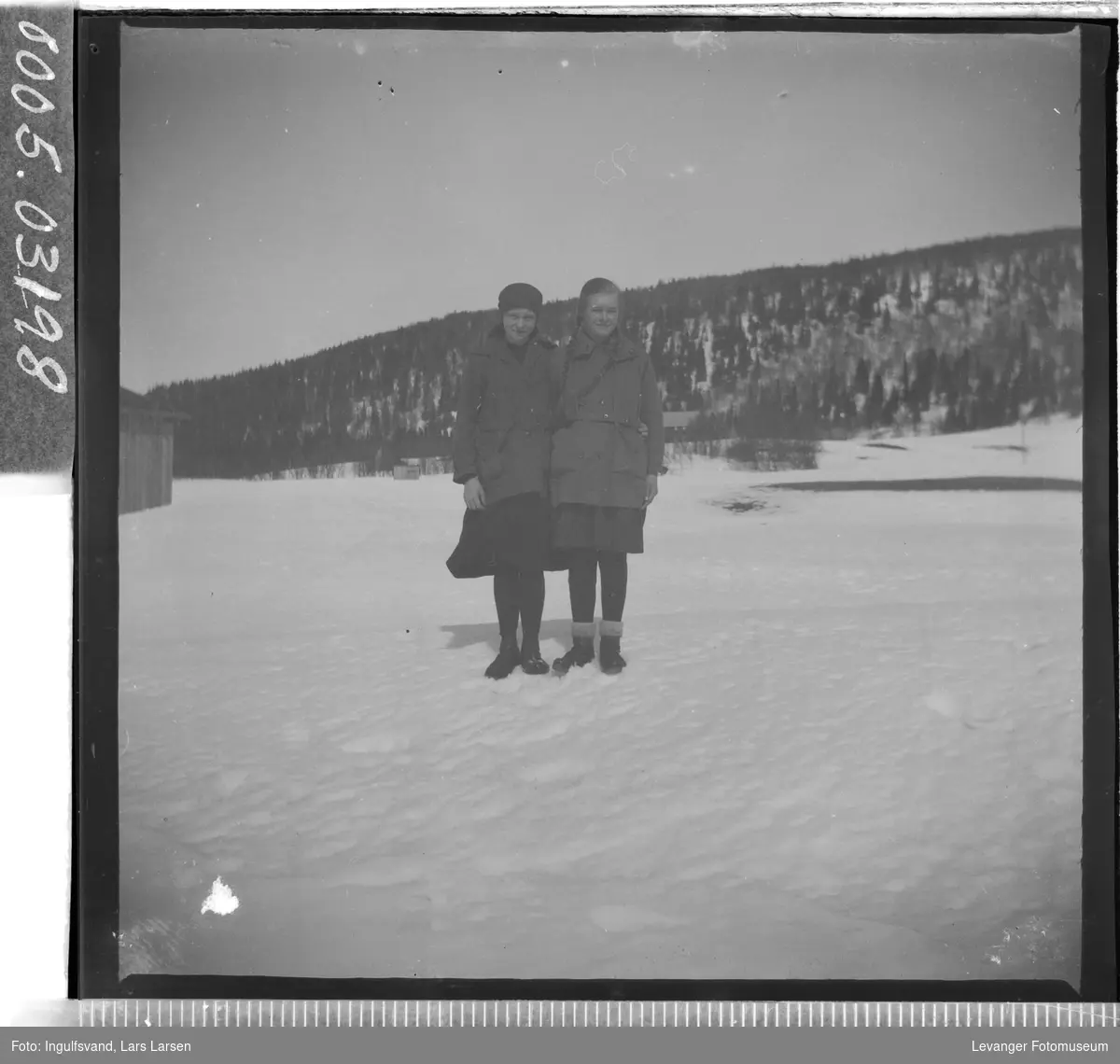 Portrett av to jenter stående i snøen.