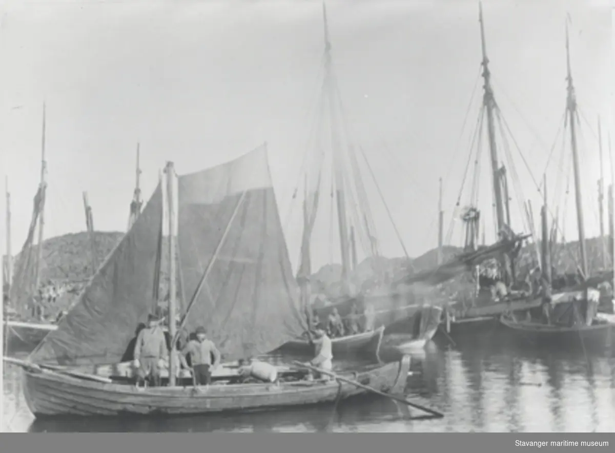Hardanger garnbåt med seil i Rogaland ca. 1893. Tre fiskere ombord og andre båter i bakgrunnen.