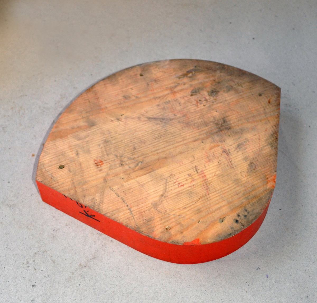 Støpemodell av tre med skruehull. Skive til å bygge opp porthengslene med. Oransj farge og to sorte prikker på.