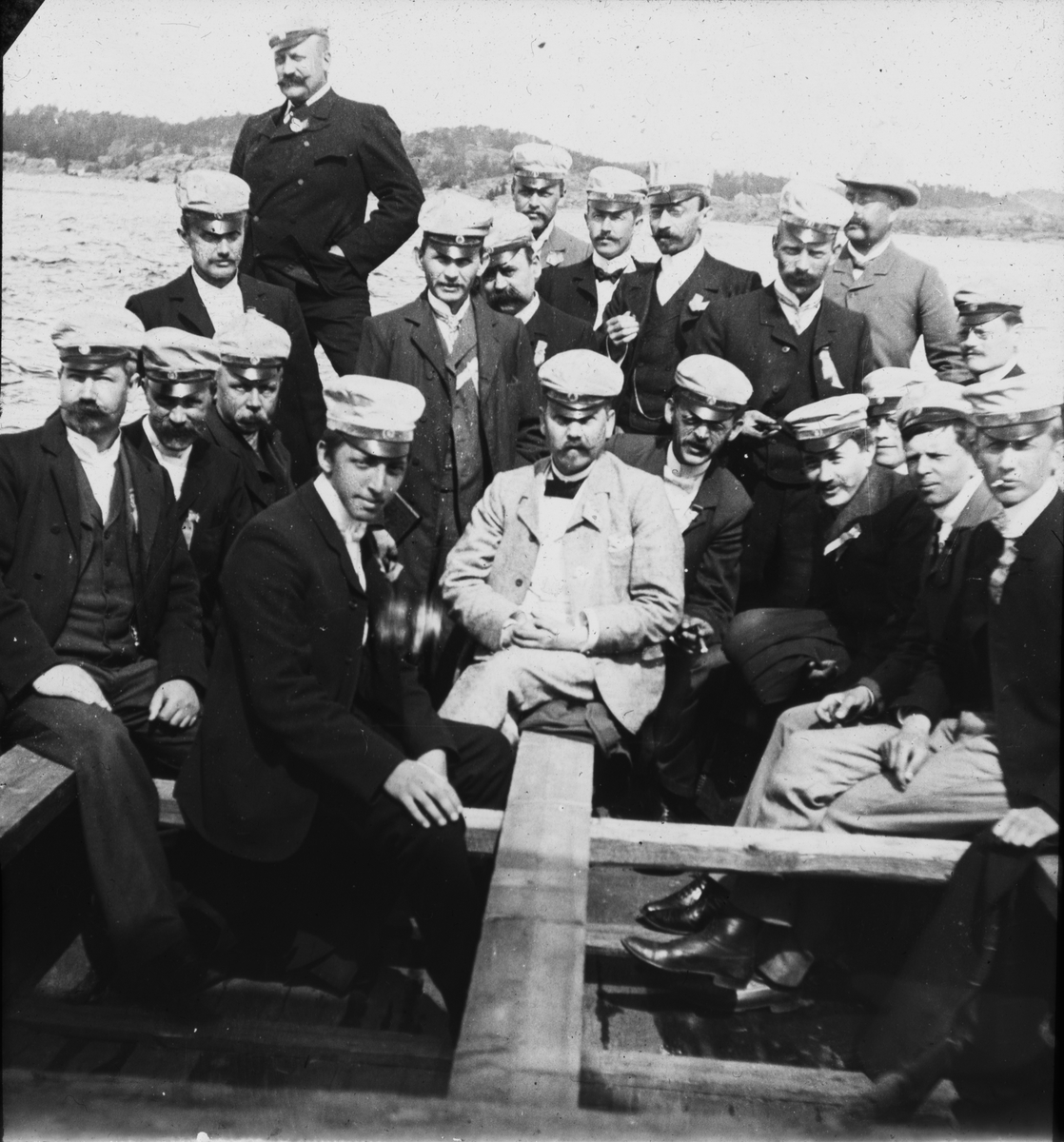 Herrer med luer ombord i båt i Kragerø.