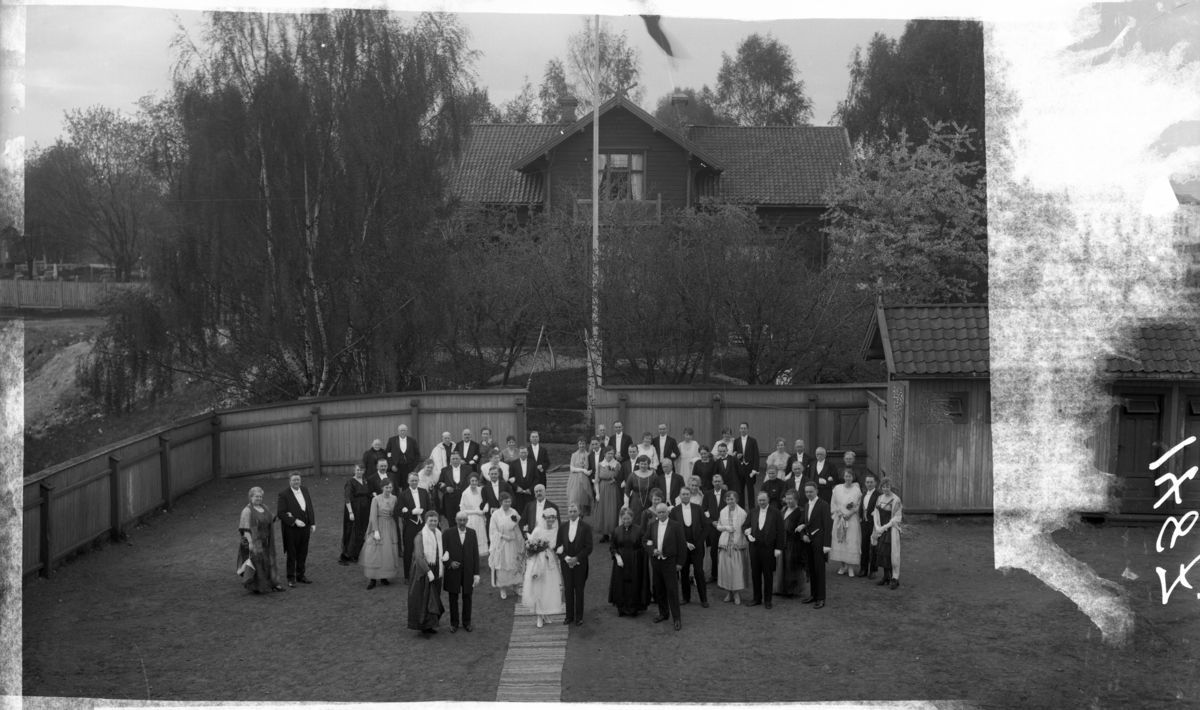 Brudepar med flere fotografert i hagen. Bryllup i Holbergs gate 27. foreldrene til Sonja haraldsen. Se bok om kronprinsesse Sonja, hvor bildet er gjengitt med opplysninger.