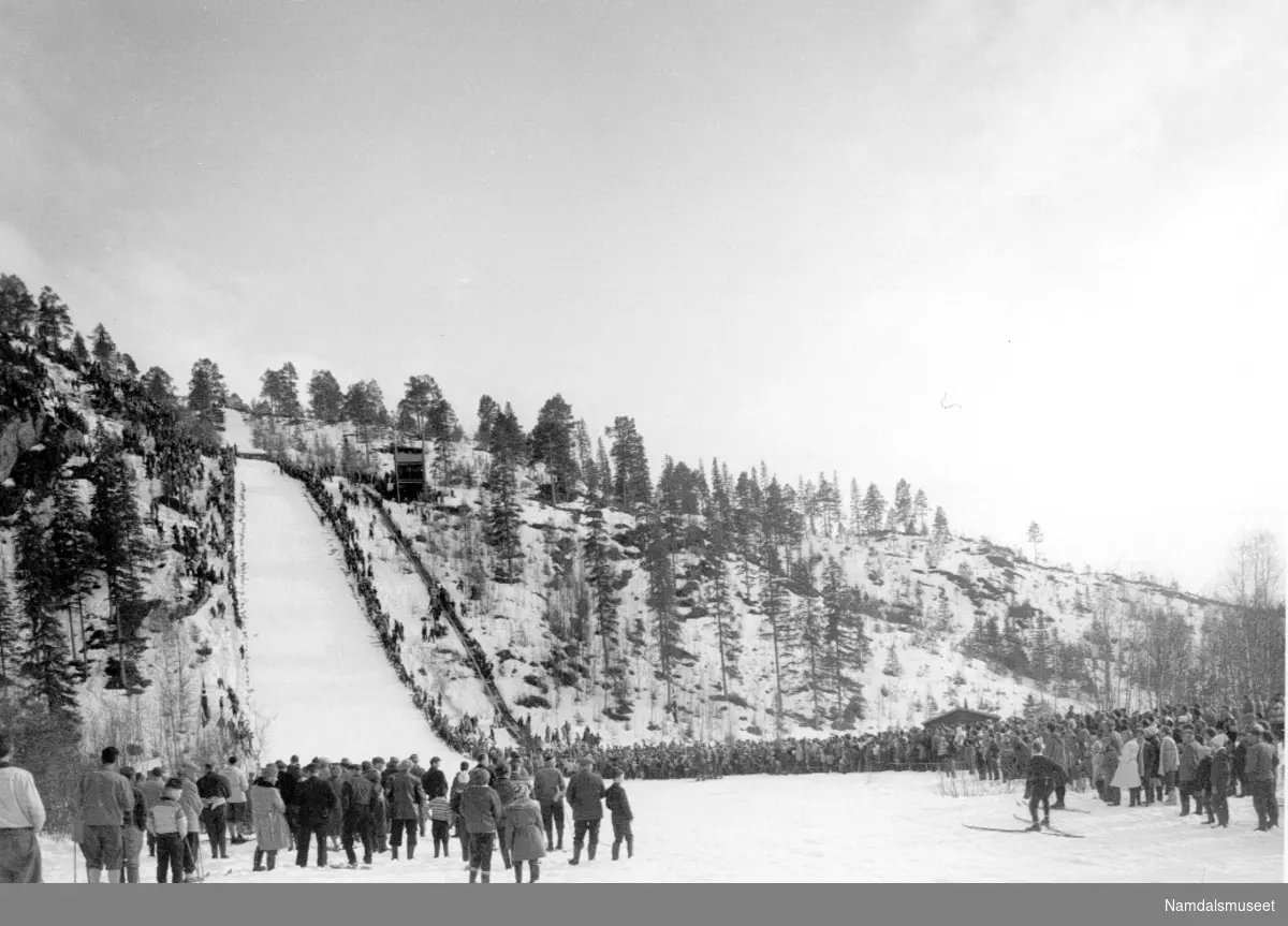 Ski, hopp. Bilde fra et hopprenn i Granåsen. Det er mye folk som ser på. (Kan være fra det storrennet som var der i 1960.)