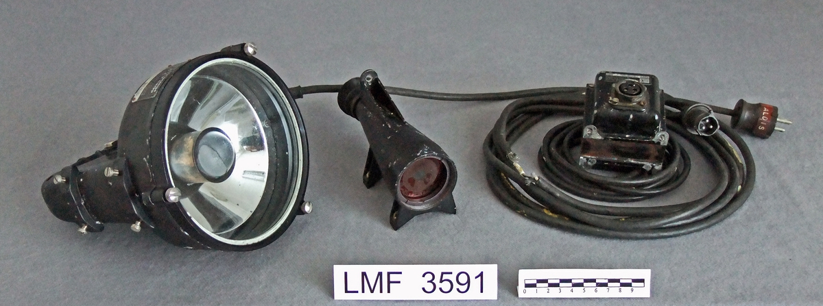 Signallampe / morselampe med tilhørende, låsbar kasse. Denne signallampa har vært benyttet i åpen sjø  (til havs) for å signalisere mellom skip  v.h.a. morse-koder.

Form:  lampefronten sirkulær, transformatoren samt kassa rektangulær.