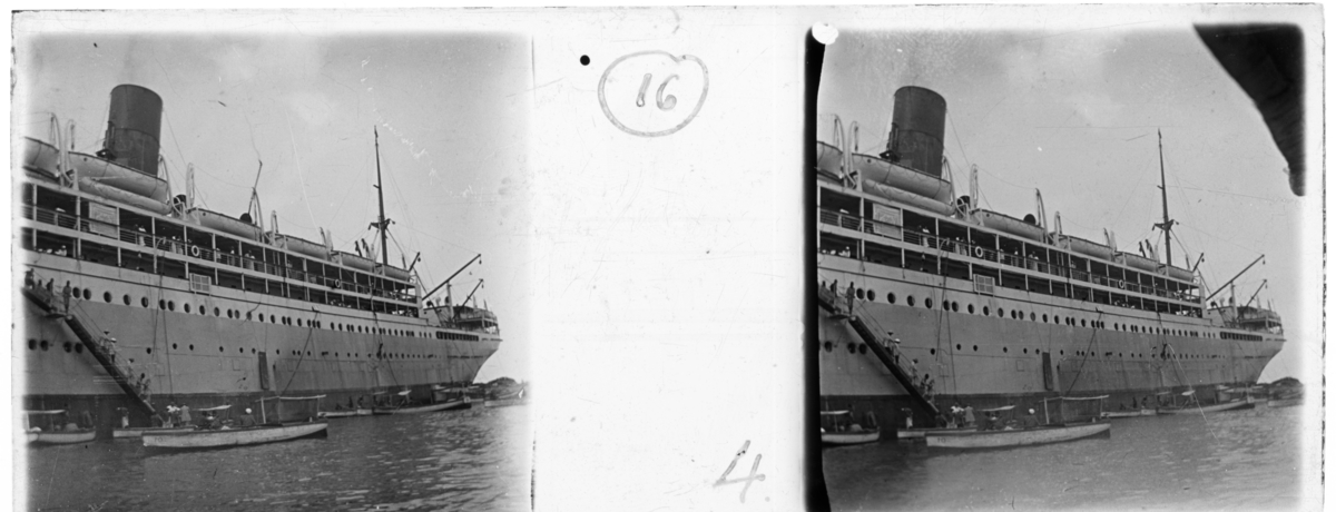 'Stor båt med ett antal mindre båtar liggande intill. Människor går uppför trappa från småbåtarna till stora båten. :: Enligt text till fotot: ''At Mombasa, from tender boat.'' (Vid Mombasa, från ::  ::  :: Ingår i en serie med fotonr. 5240:1-17. Se även fotonr. 5237:1-16, 5238:1-18 och 5239:1-18, 5241:1-18.'