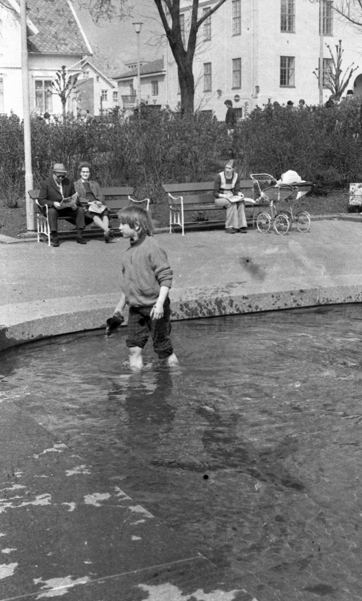 Bilder fra Rådhusparken. Barn som leker i vannet. Flere personer nyter været på benkene i parken.