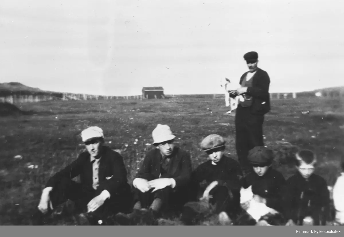 Fem brødre er fotografert sittende på bakken med sommerfjøset i bakgrunnen.  Fra v. eldstemann Erling, Hendry, Odd, Harald og Trygg. Faren Sevalders står bak og holder hunden Flink i armene.