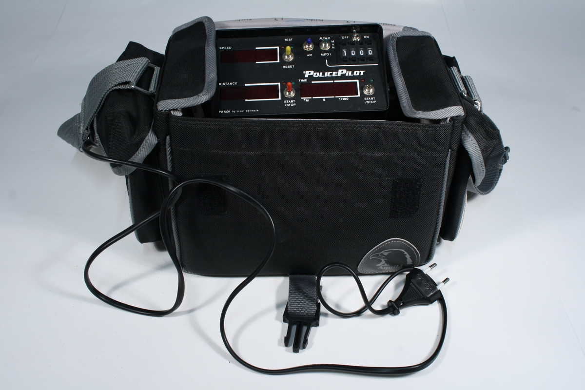 Elektronisk apparat montert på stativ. Oppbevart i en grå bag med sidelommer og bærestropp.