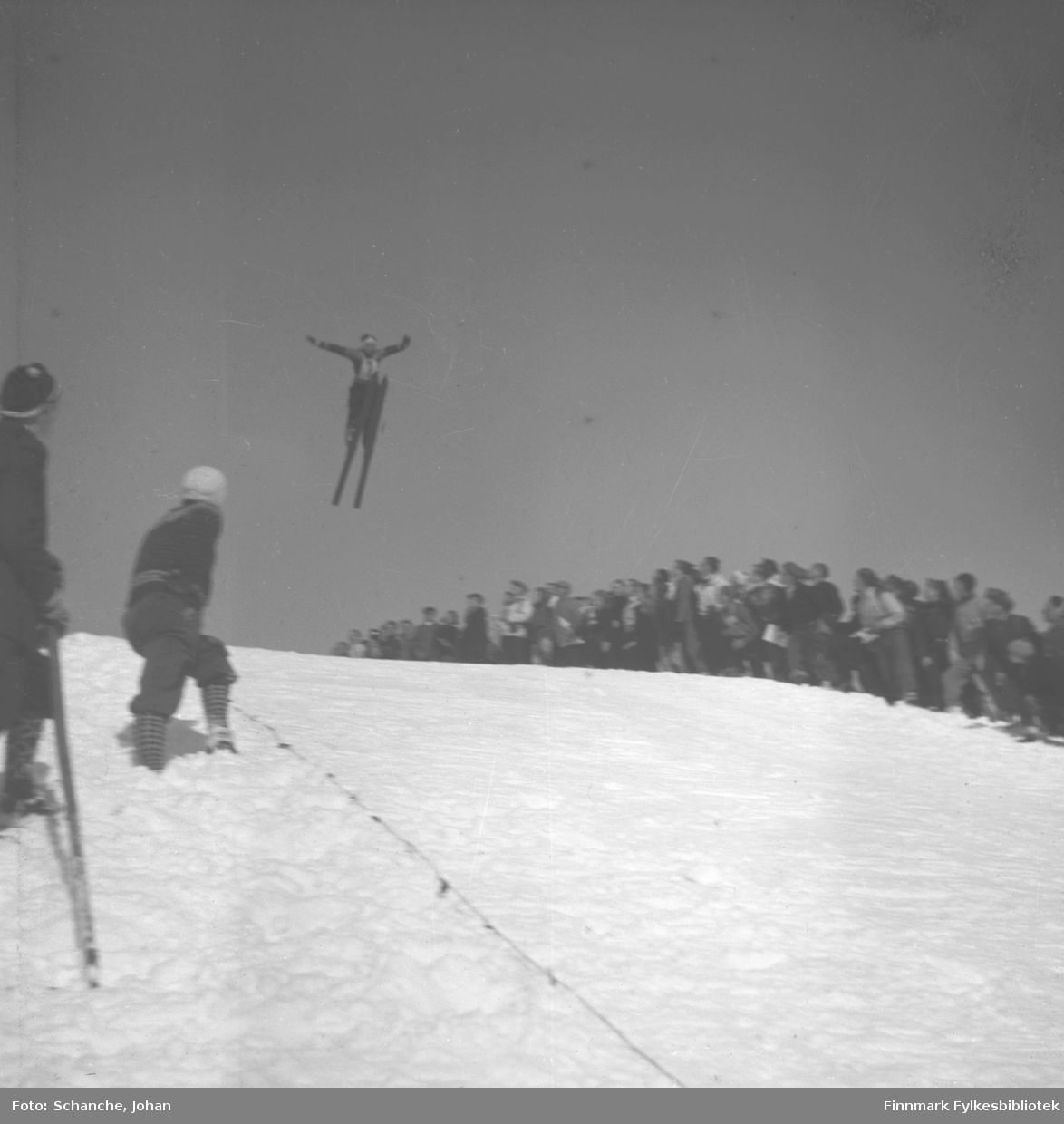 Kretsrennet på ski , Vadsø 1946. Høgstad fra Kirkenes hopper. Vi ser publikum i bakgrunnen og trolig de som måler hopplengden til venstre.