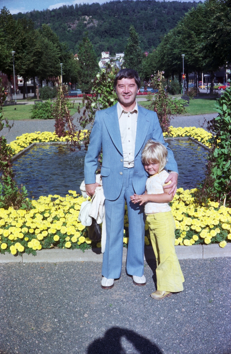 Brottaren Tore Damberg med dotter på Esplanaden i Huskvarna. Runt dammen bakom dem är gula tagetes planterade.