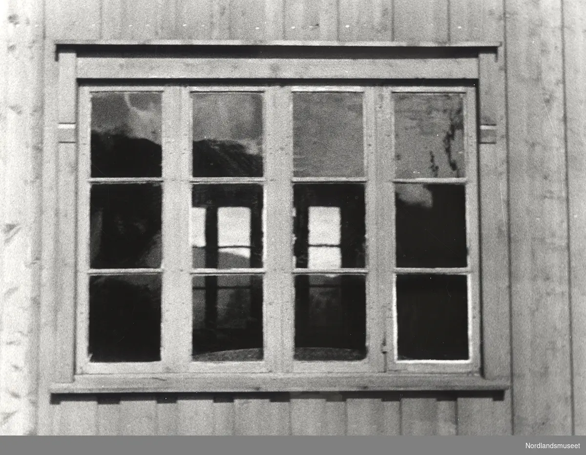 Vindu på hovedbygningen, Hemnes bygdetun. Et vindu med fire avlange vinduer som er rutede. På veggen rundt vinduet er det stående trepanel.