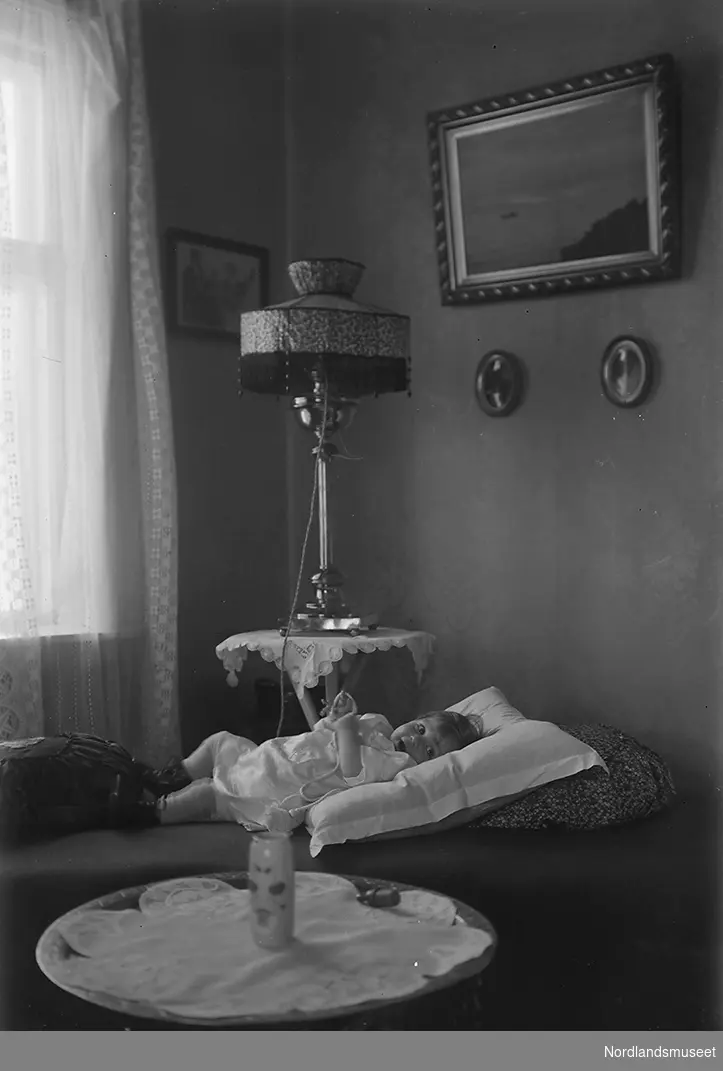 Et pikebarn ligger på en divan. Barnet kan være Else "Lillemor" Lund eller Anders Forsdahls første barnebarn. Bildet er sannsynligvis tatt i Sulitjelma.