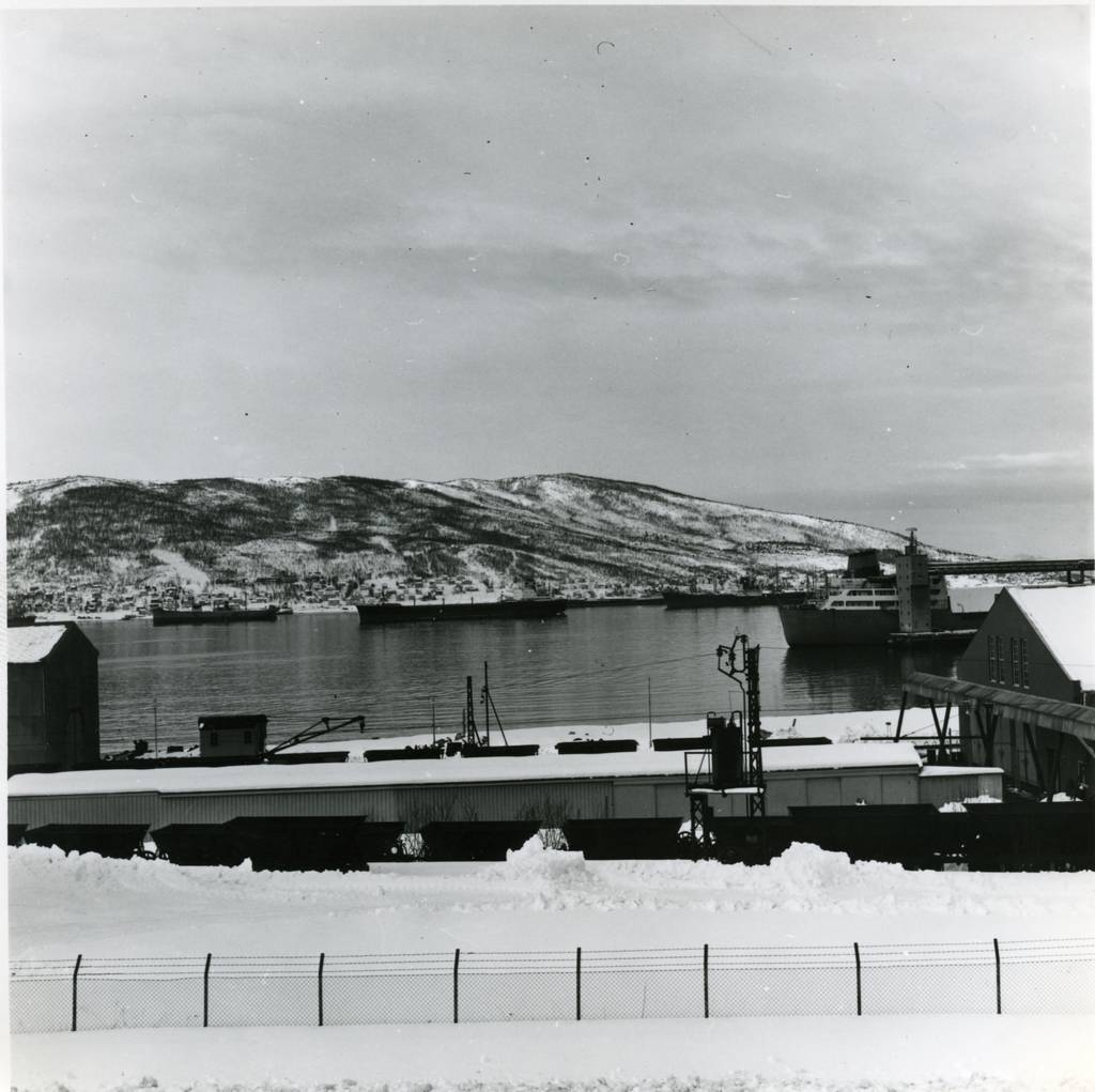 LKAB. Til høyre Vognverkstedet med travers til forflyttning av hjulganger mellom spor. Delelager. Narvik havn med malmbåter. Ankenes i bakgrunnen.