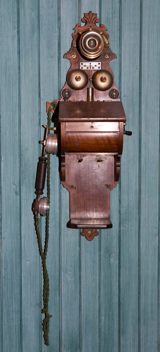 Telefonapparat på en avlang treplate til å henge på veggen.