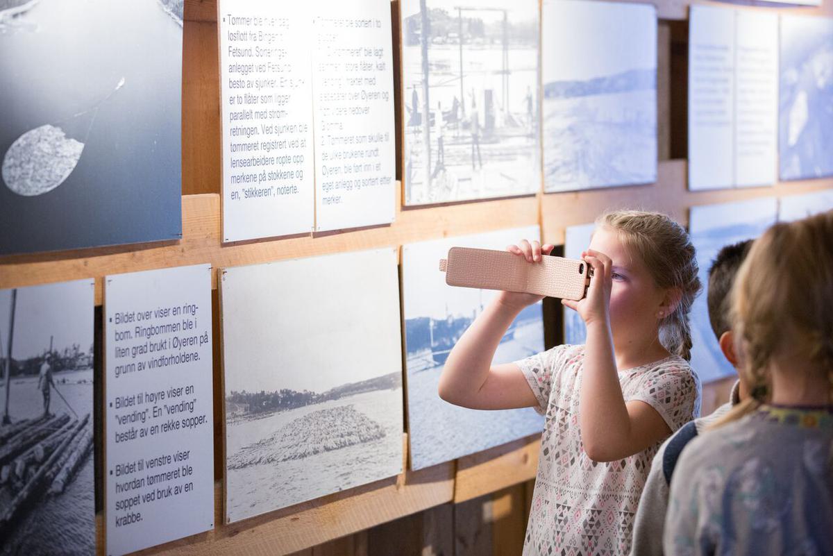 Barn som ser på utstilling av fløtingshistorie