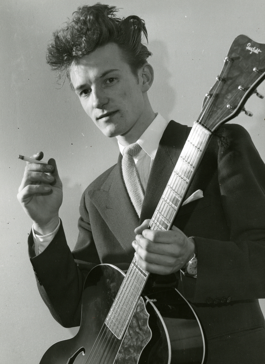 Ung mann med gitar som røyker.