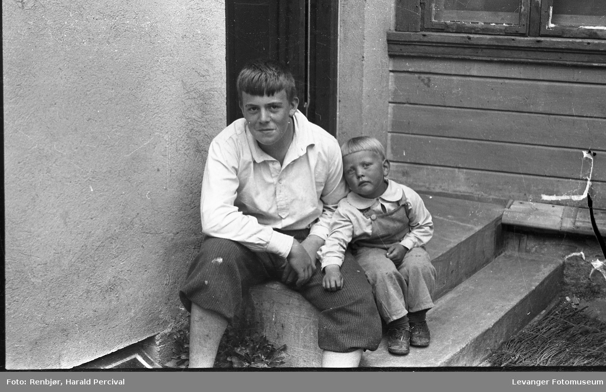 Per Renbjør og en liten gutt på trappa ved Renbjørs foto- og musikkforretningen.