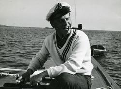 Man ved roret i seilbåt røyker pipe.