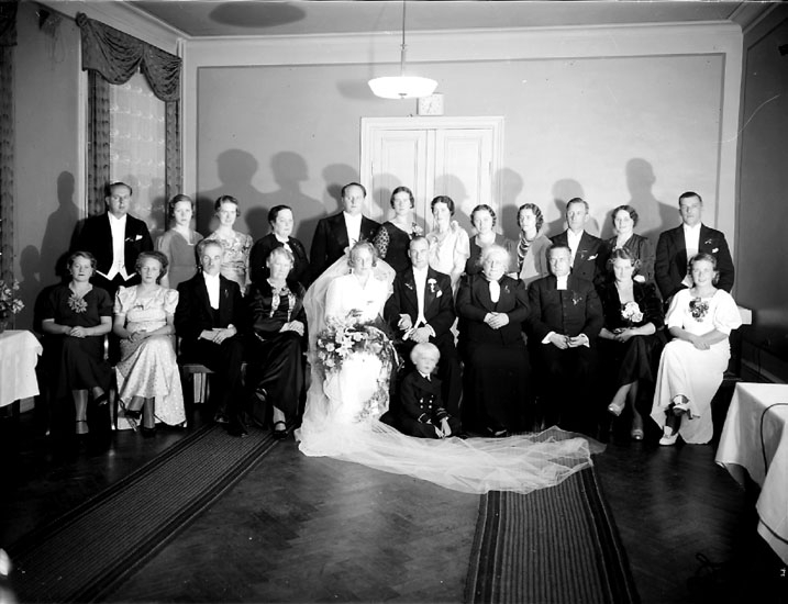 Bröllop, brudpar och bröllopsgäster inomhus.
Olssons kläder, Drottninggatan 30, Örebro.