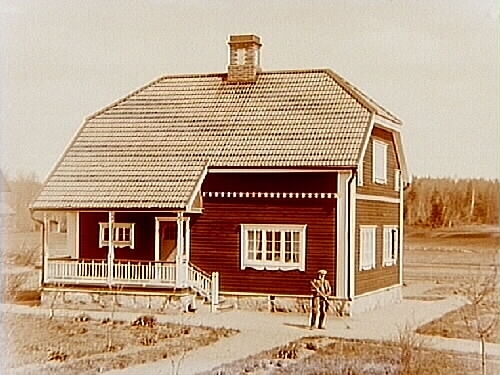 En och en halvvånings bostadshus med brutet tak och förstebro.
Agronom Persson