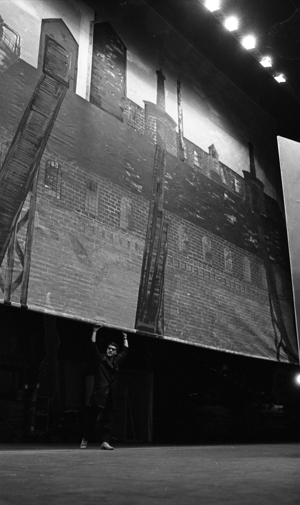 Bergmanteater, Största fabriken 14 januari 1967

En man står på en scen på teatern och drar ner en ridå, som föreställer en byggnad.