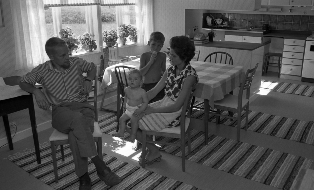 Huset Tvären 23 juli 1966

En pojke äter glass i köket, med sin familj.
Trasmattor.
Interiör.