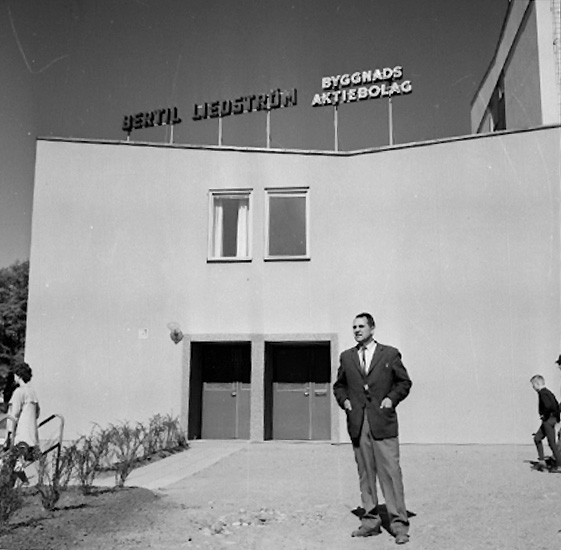 En man. Direktör Bertil Liedström
. Fabriksbyggnad i bakgrunden.
Bertil Liedström Byggnads AB byggde bl. a. polishuset på Stortorget.