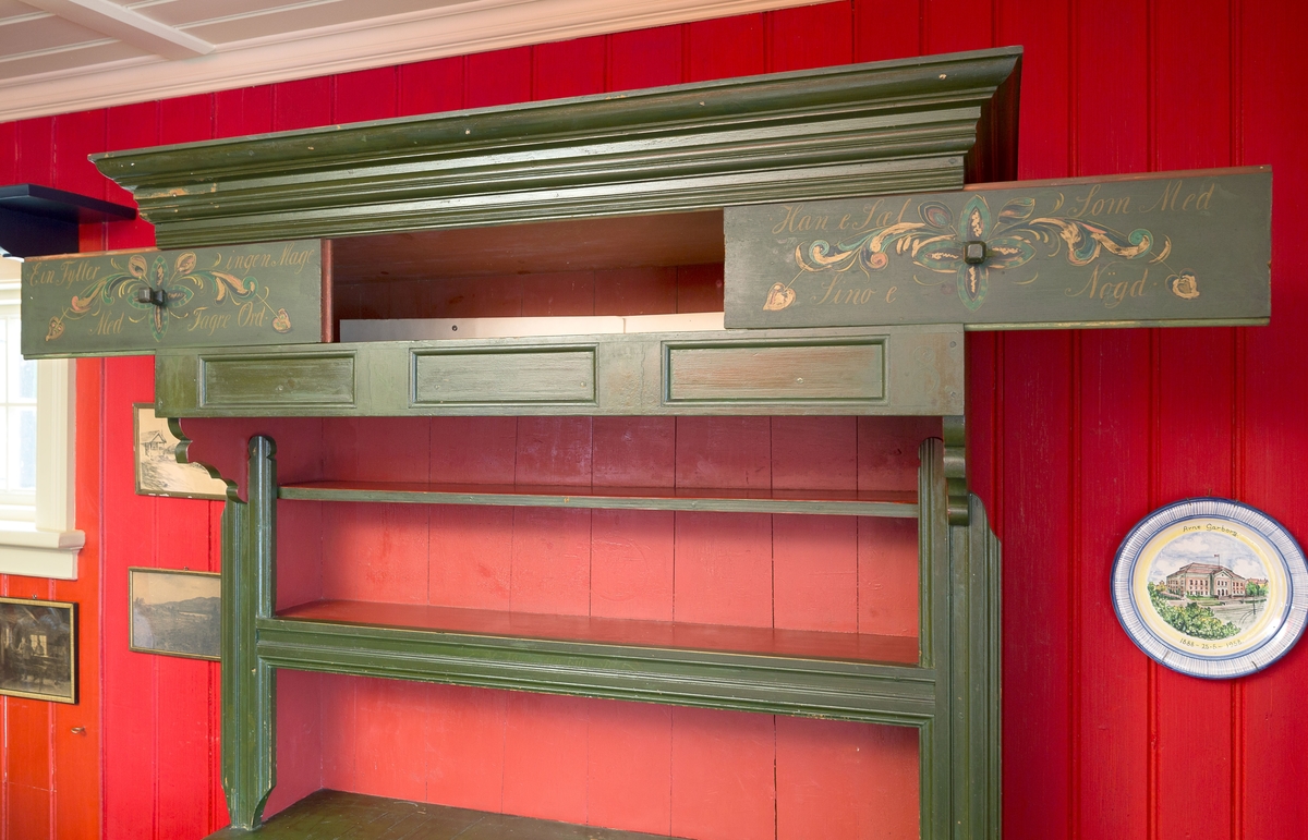 I dør og sider på underskap kryss som er malt.  2 Rosemalte skyvedører m/tekst på skap  øverst, 2 hyller og underskap m/1 hylle. Lite skap i høyre side. Skuff til bestikk.