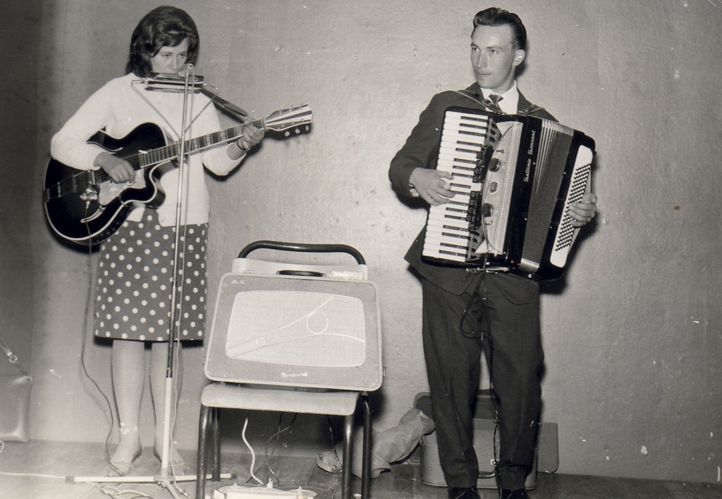 Duo, lite "band", kvinne med gitar og munnspel, mann med trekkspel.
(Ingenting notert av registrator.)