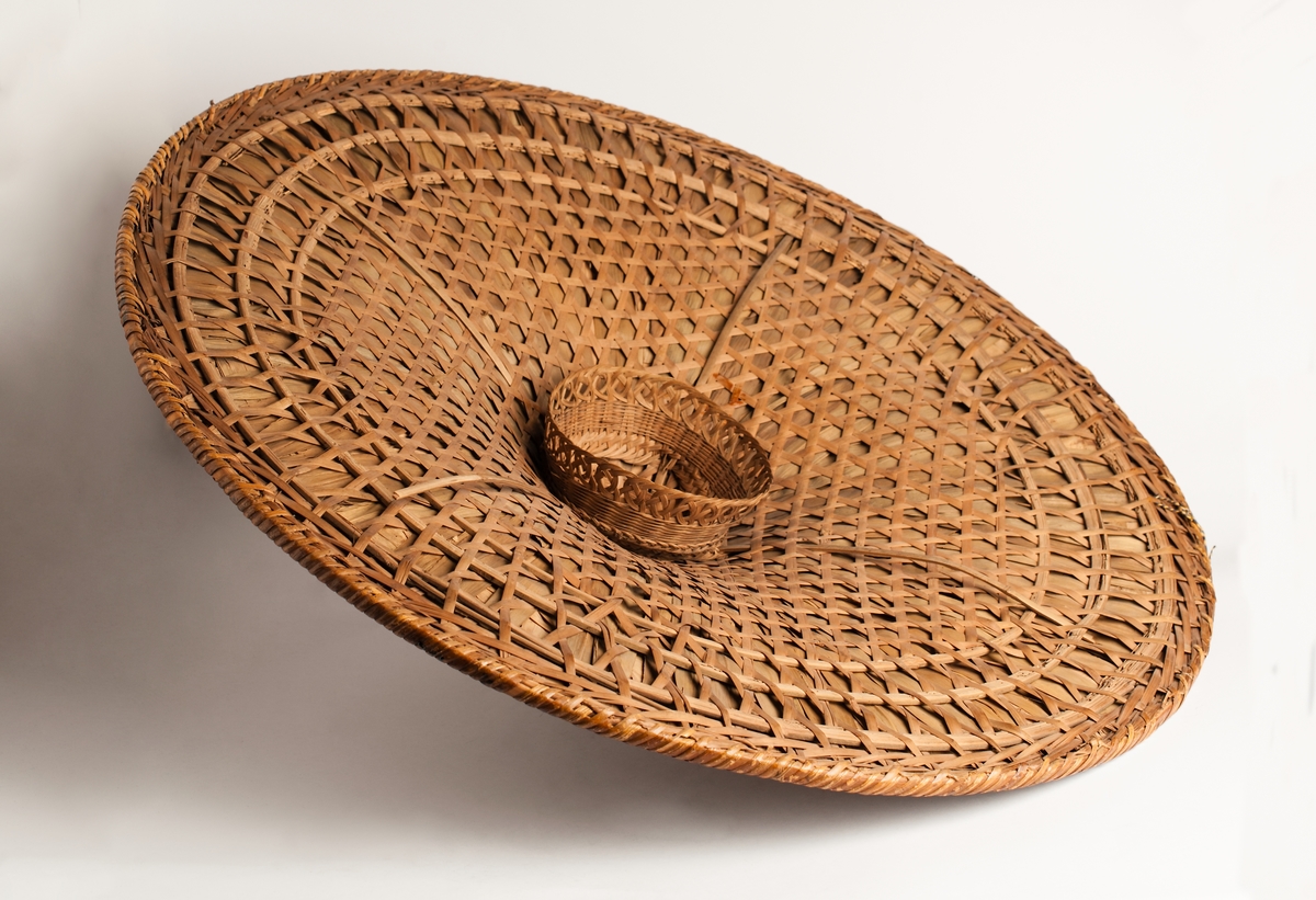 Hatt från Kina av flätad bambufiber och palmblad, konisk, insvängd, bred bas. Stor men lätt.
Från fregatten Vanadis världsomsegling 1883-1885.
