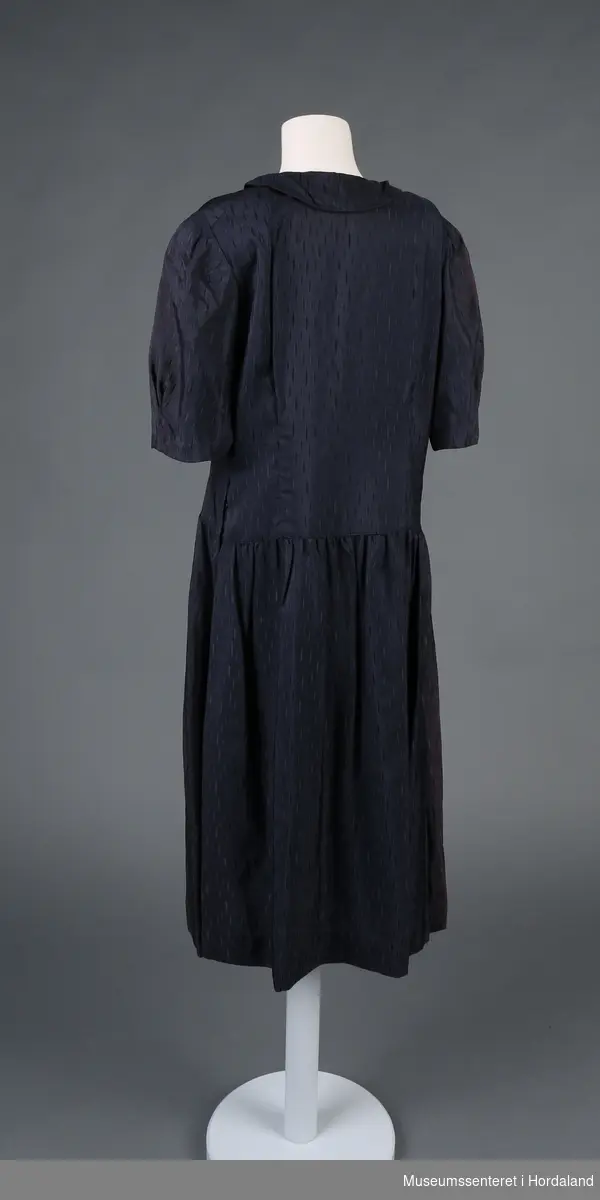 Form: korterma kjole, med rynka skjørt og patentknapping framme, rund krage
