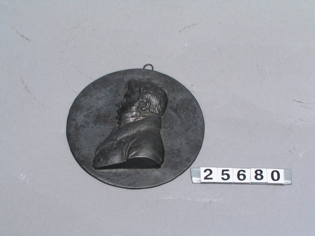 Liten medaljong i gjutjärn över J.J. Berzelius. Möjligen gjuten efter förlaga i vax signerat "Posch 1822".
