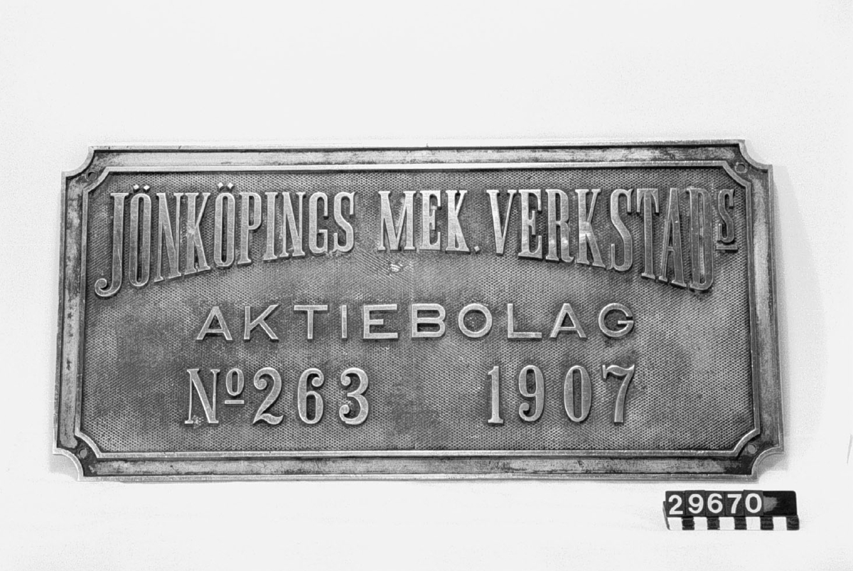 Väggplåt av förnicklat gjutgods. Text: Jönköpings Mekaniska Verkstads AB, 1907. Nr 263.