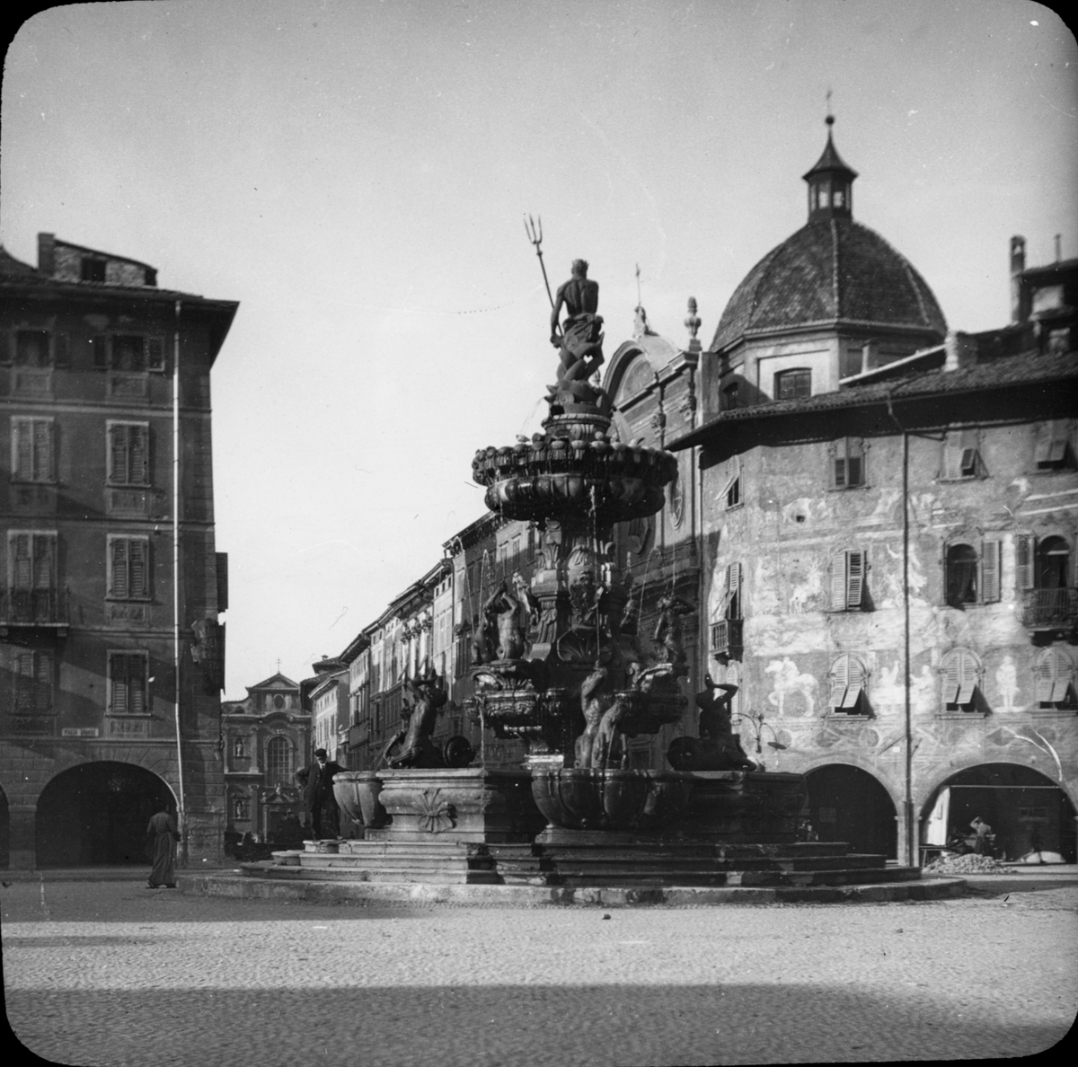 Skioptikonbild med motiv av Neptuns brunn, Fontana del Nettuno, på Piazza Duomo i Trento.
Bilden har förvarats i kartong märkt: Resan 1909. Trient 7. N:20.. Text på bild: "Via Largo".