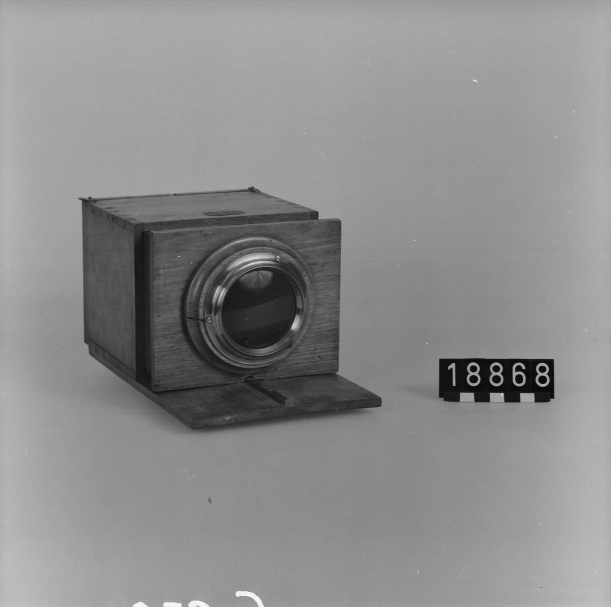Daguerreotypiapparat av trä. Skjutlådemodell avsedd att användas med stativ. Avståndsinställning med skala och visirskiva. Kameran saknar bländare och slutare. Exponering görs med hjälp av ett objektivlock. Tillbehör: En kassett av trä och visirskiva med spegel.
